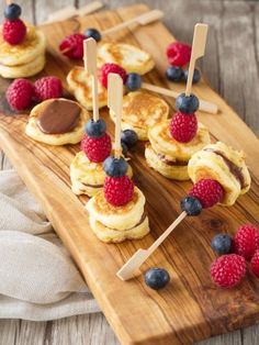 pancakes with raspberries and blueberries on a wooden platter, ready to be eaten