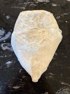 a piece of plastic wrap sitting on top of a black tablecloth covered in water