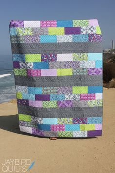 a woman holding up a quilt on the beach