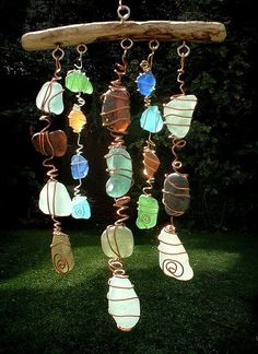 a wind chime hanging from a tree branch on top of green grass with lots of different colored glass beads