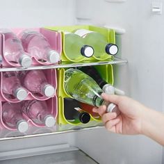 a person is holding a bottle in front of a refrigerator with several containers on it