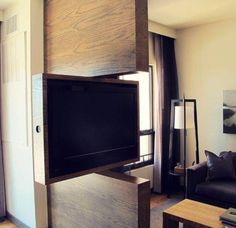 a flat screen tv sitting on top of a wooden shelf in a living room next to a window