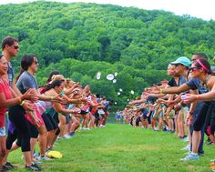 a group of people standing on top of a lush green field next to each other