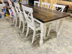 a wooden table with white chairs around it