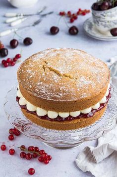 a cake sitting on top of a glass plate covered in icing and cherries