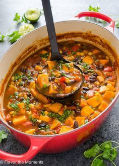 a red pot filled with black bean and sweet potato soup on top of a table