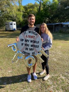 a man and woman standing next to each other holding up a sign that says it would light up my world if you would be my coach