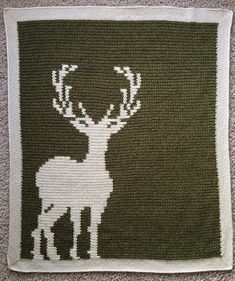 a knitted rug with a deer and antelope on the front in white