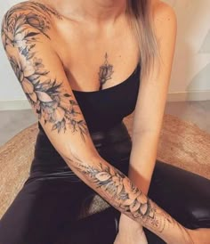 a woman sitting on the floor with her arm tattooed