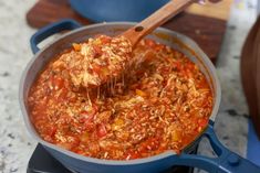 a wooden spoon scooping some food out of a pot