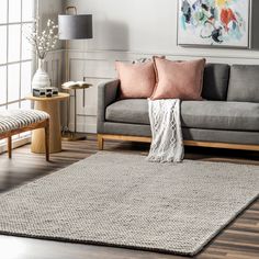 a living room scene with focus on the grey couch and rug, along with two side tables