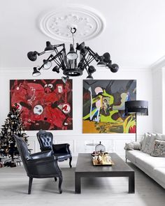 a living room filled with furniture and a christmas tree in front of two paintings on the wall