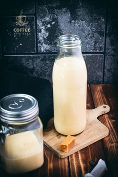 a glass jar filled with milk next to a wooden cutting board and bottle of butter