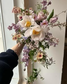 a person holding a bouquet of flowers in front of a window