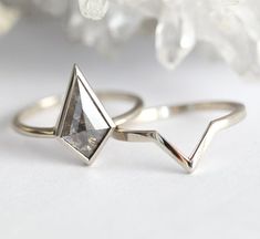 two silver rings sitting next to each other on top of a white table with crystals