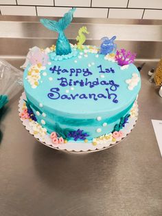 a birthday cake that is on top of a metal counter with the words happy 1st birthday savannah written on it