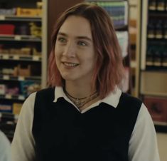 a woman with red hair standing in front of a store filled with shelves full of drinks