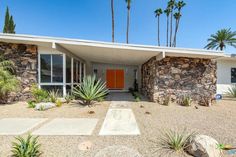 a house with rocks and palm trees in the background