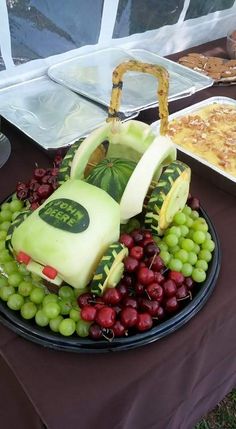 a table topped with plates and trays filled with grapes, watermelon and cheese