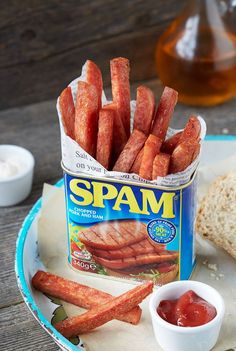 a can of spam sitting on top of a table next to bread and ketchup