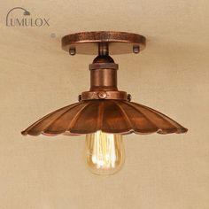 an old fashioned light fixture with a bulb on the ceiling and a wall in the background