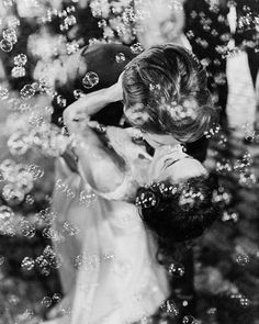 a black and white photo of a woman blowing bubbles in the air with her hands