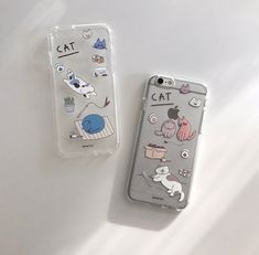 two cell phones sitting next to each other on top of a white table with stickers