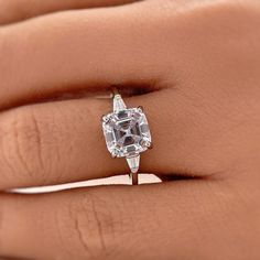 a woman's hand holding an engagement ring with a large white diamond in the center