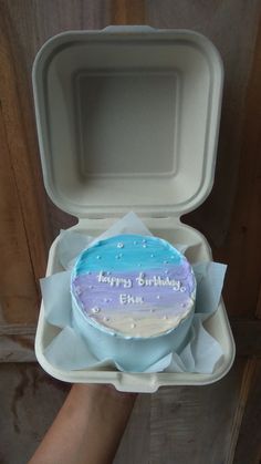 a birthday cake in a foam box with the lid open to show it's frosting