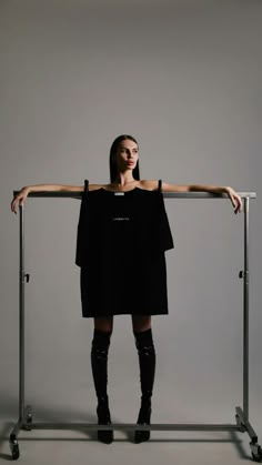 a woman standing behind a metal rail with her arms on the top and legs crossed