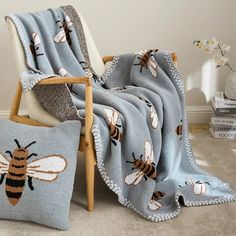 a chair with two pillows on it and a blanket that has bees printed on it