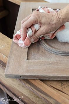 a person wiping up some wood with a rag