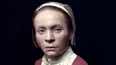 a woman with blue eyes wearing a red sweater and a white headband is looking at the camera