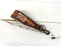 a keychain with a flower design on it sitting on a white wooden surface