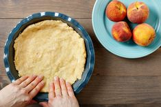 two hands reaching for a pie crust on a table with peaches in the background