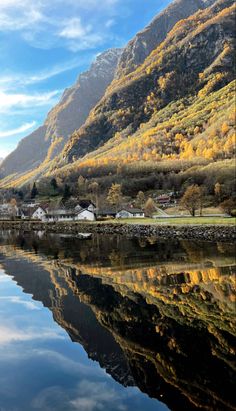 the mountains are covered in autumn foliage and reflecting in the still water on the lake