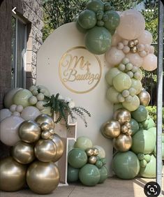 the balloon arch is decorated with gold and green balloons