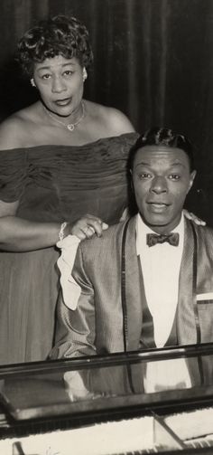 an old black and white photo of two people standing next to each other in front of a piano