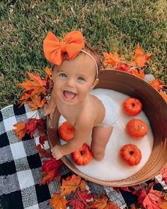 a baby sitting in a tub filled with foamy water and pumpkins on the ground