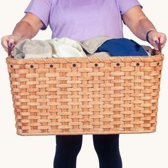 a woman holding a basket full of clothes with her hands on the top of it