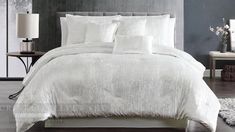 a bed with white comforters and pillows in a room