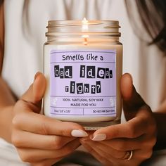 a woman holding a candle that says, smells like a bad idea right now?