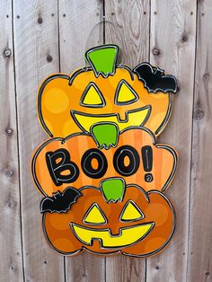 a wooden fence with a sign that says boo on it and two pumpkins in the background