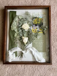 an open book with flowers in it on the floor next to a white ribbon and some other items