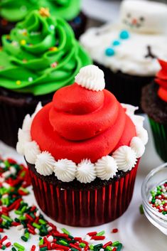 cupcakes decorated with red, white and green frosting are on a table