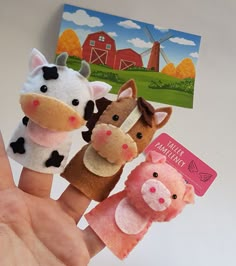 four finger puppets are placed in the palm of someone's hand, with farm animals on them