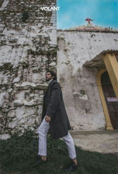 a man standing in front of a stone wall with the words volant on it