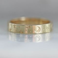 Why I Love It: A band that is perfect for any time of day or night in this wider version of our best selling engraved bands. Swift and careful hand movements create this motif of crescent moons, stars, planets and sun rays. Engraved texture with precise detail and extraordinary design in your choice of golds. All hand engraved locally in San Francisco, CA. The Details: 14k Yellow Gold, 14k White Gold, 14k Rose Gold, 18k Peach Gold Band Width is Approx. 3.50 mm Made to order in your size, please Engraved Gold Band, Celestial 14k Gold Round Band Jewelry, Celestial Style 14k Gold Round Band Jewelry, Celestial Jewelry With Sun And Moon Design For Promise, Adjustable Celestial Engraved Jewelry, Celestial Crescent Engraved Jewelry, Gold Celestial Engraved Ring As Gift, Engraved Moon Shaped Jewelry For Wedding, Engraved Moon Shaped Wedding Jewelry