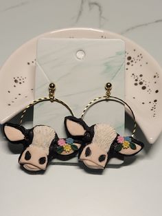 pair of cow earrings on white plate with marble background