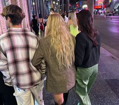 three people walking down the street at night